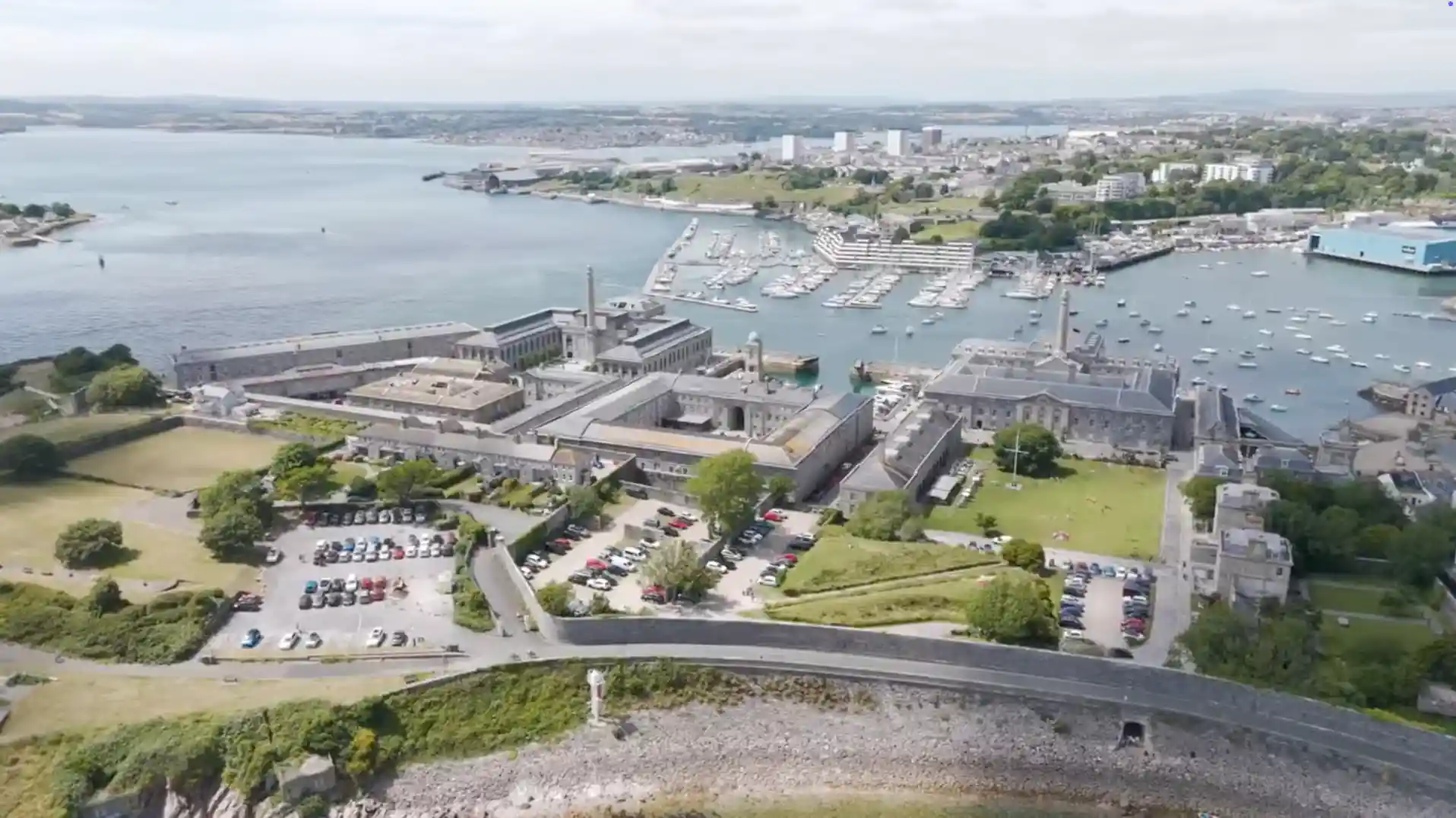 Aerial view of Royal William Yard in Plymouth, showing historic naval buildings, surrounding lawns, and Millbay Marina filled with boats.