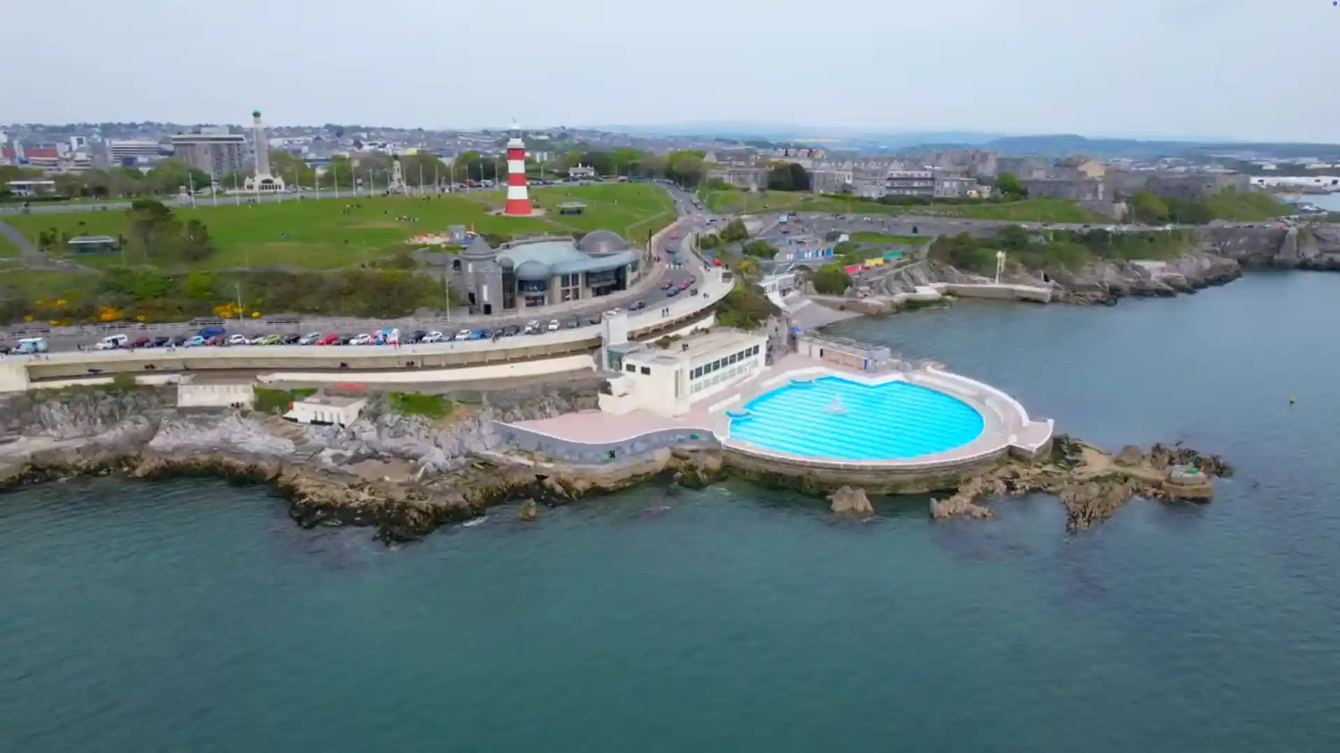View of Tinside Lido and Plymouth Hoe from above, with the sea pool, Smeaton’s Tower, and Hoe parkland in the background.